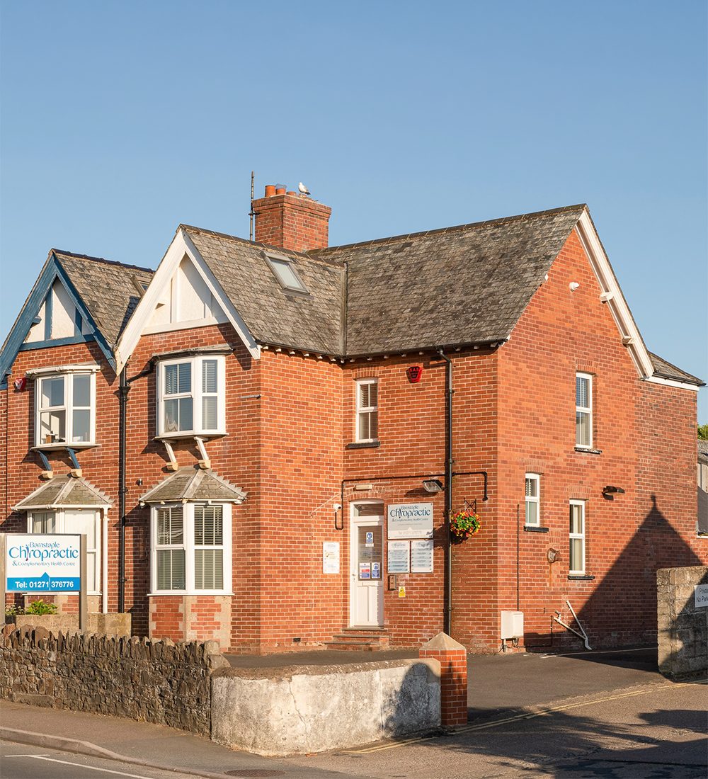 The red-brick exterior of the Barnstaple Chiropractic & Complementary Health Centre in Sticklepath, in warm evening light